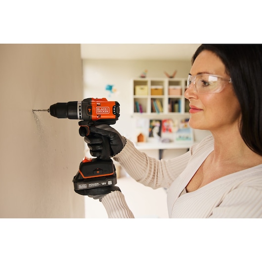Photo d'une personne utilisant une perceuse sans fil BLACK+DECKER BLD683XN sur un mur en intérieur.