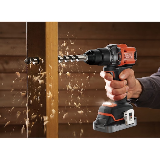 Perceuse sans fil BLACK+DECKER BLD683XN en action perçant du bois, copeaux projetés, vue rapprochée latérale.