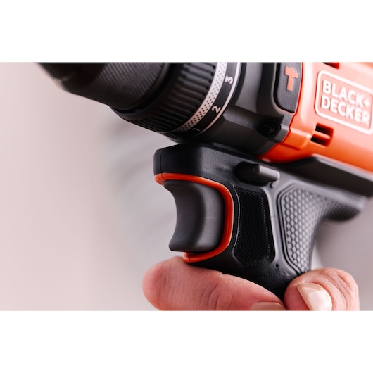 Photo en gros plan de la poignée et la gâchette de la perceuse BLACK+DECKER BLD683XN en main, prise texturée noire et orange.