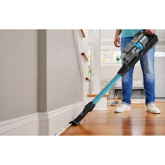 BLACKDECKER BSV520BRB steelstofzuiger reinigt vloerplinten in een modern huis, blauw en zwart ontwerp.
