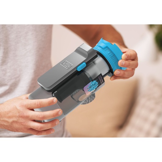 Close-up van BLACK+DECKER BSV520BRB stofreservoir met blauwe deksel, vastgehouden voor filterreiniging.