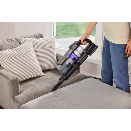 BLACKDECKER BSV520BRP draadloze steelstofzuiger reinigt een grijze bank in een huiselijke omgeving.
