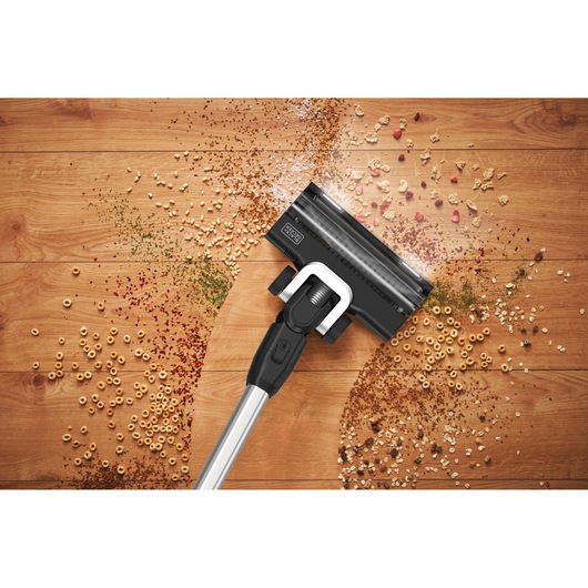 BLACKDECKER BSV520BRP draadloze stofzuiger reinigt ontbijtgranen en kruimels op houten vloer, bovenaanzicht.