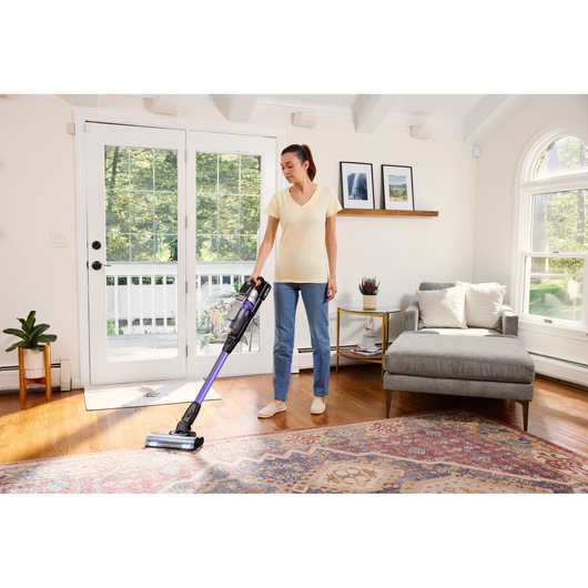 BLACKDECKER BSV525BRP snoerloze steelstofzuiger met paarse steel gebruikt op hout en tapijt in een woonkamer.