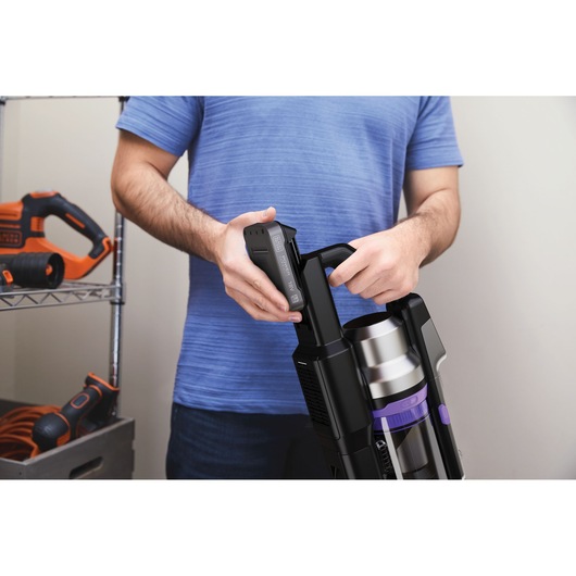 BLACKDECKER BSV525BRP snoerloze stofzuiger accu wordt geplaatst door persoon met blauw shirt, binnenshuis.