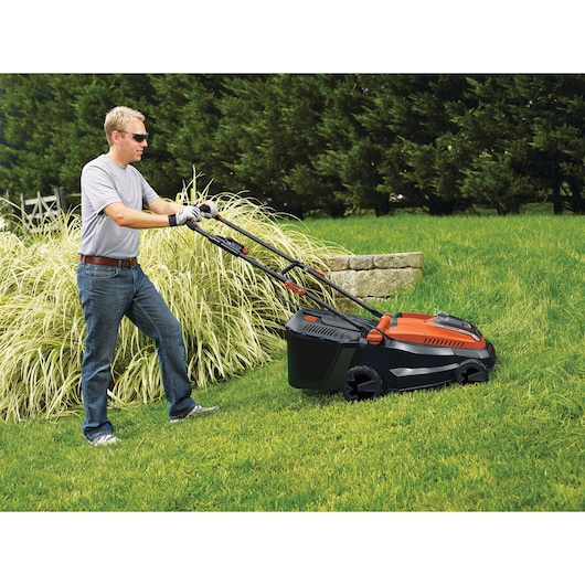 BLACKDECKER CLM3825L2 tondeuse utilisée sur pelouse, vue latérale, design orange et noir, extérieur.