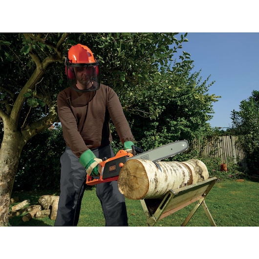 BLACKDECKER CS1840 kettingzaag zaagt hout buiten, gebruiker met beschermende uitrusting, categorie fotografie.