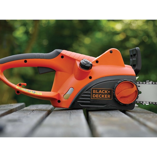 BLACKDECKER CS2040 oranje-zwarte elektrische kettingzaag zijaanzicht op houten oppervlak buiten.