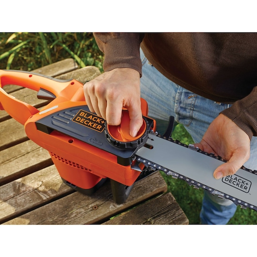 Close-up van BLACK+DECKER CS2040 kettingzaag, gebruiker stelt kettingspanning buiten af.