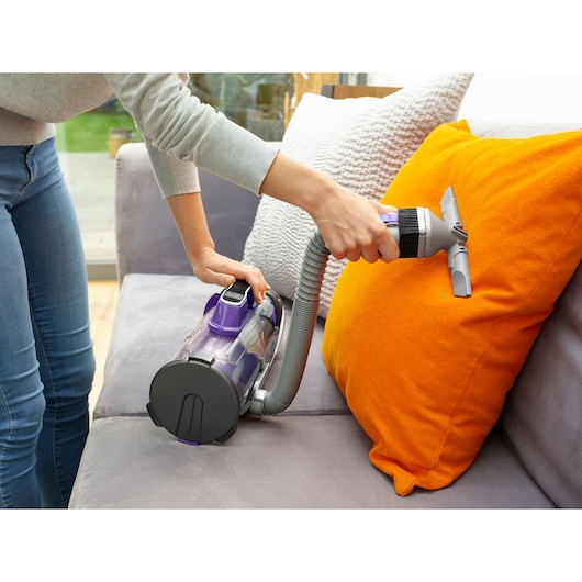 BLACKDECKER CUA625BHP aspirateur utilisé sur coussin orange, nettoyage de canapé, scène de photographie.