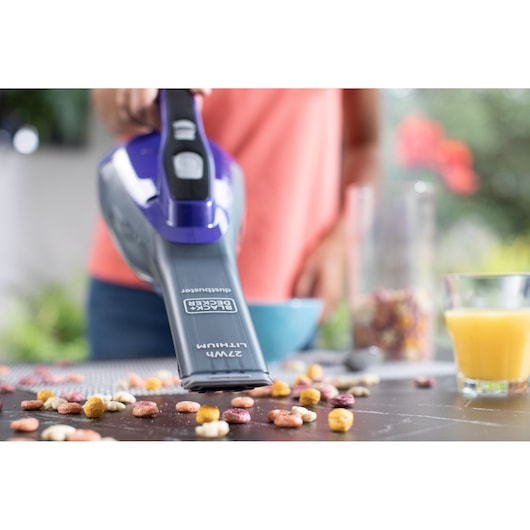 BLACKDECKER DVA325JP07 handstofzuiger zuigt ontbijtgranen van tafel, close-up fotografie.
