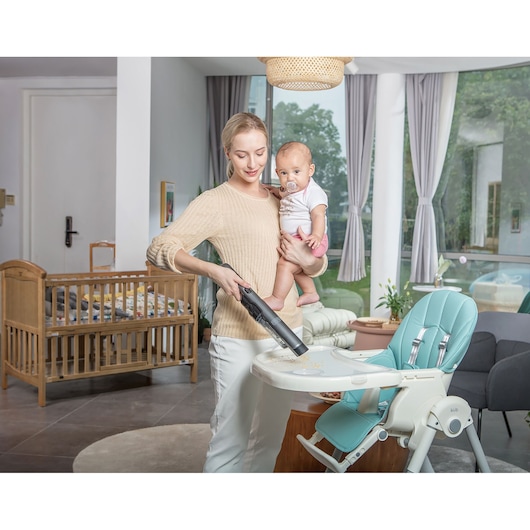 BLACKDECKER DVC320B21 handstofzuiger wordt gebruikt om een kinderstoelblad schoon te maken in een moderne woonkamer.