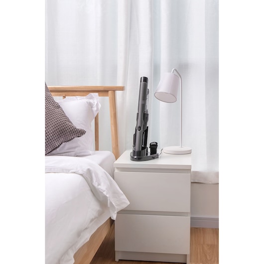 BLACKDECKER DVC320B21 snoerloze handstofzuiger op wit nachtkastje naast moderne lamp in slaapkamer.