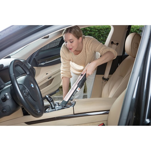 BLACKDECKER DVC320BRG handstofzuiger gebruikt voor het schoonmaken van beige auto-interieur.