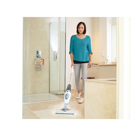 BLACKDECKER FSM1616 stoommop reinigt badkamer vloer, persoon gebruikt het apparaat.