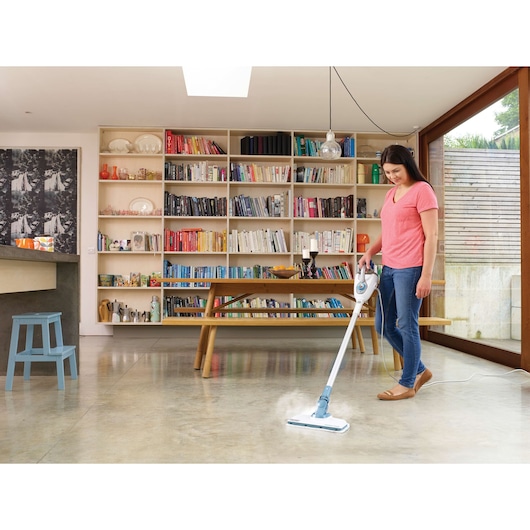 BLACKDECKER FSMH1300FX stoommop reinigt een moderne woonkamer vloer met boekenplanken op de achtergrond.