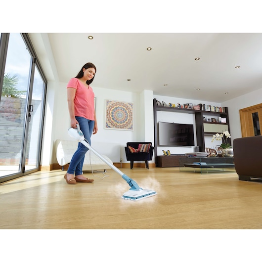 BLACKDECKER FSMH1300FX stoommop reinigt houten vloer in moderne woonkamer, fotografie vanuit zijhoek.