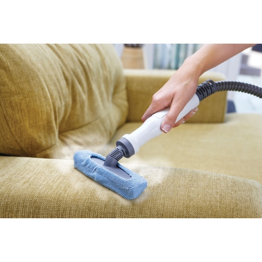 BLACKDECKER FSMH1321 stoomreiniger met blauwe microvezel pad reinigt gele bankbekleding.