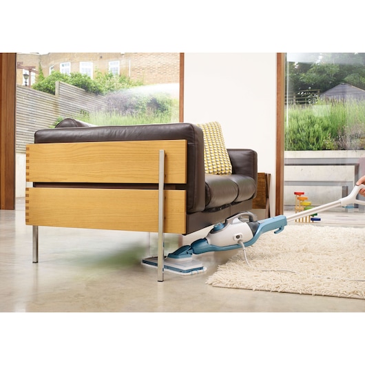 BLACKDECKER FSMH1321 stoommop reinigt onder een houten bank, lichtblauw-wit model op binnenvloer.