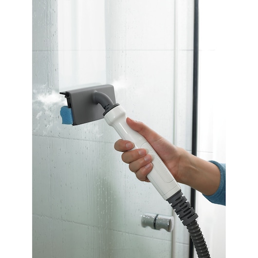 Photo de l’accessoire à main du nettoyeur vapeur BLACKDECKER FSMHBA nettoyant une porte de douche en verre.