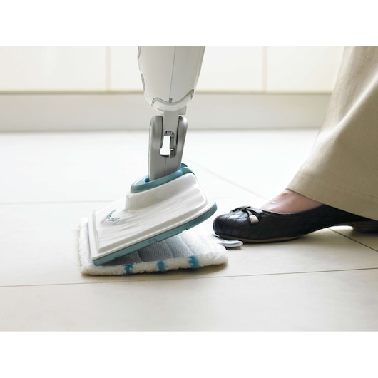 BLACKDECKER FSMP20 tête de balai vapeur avec patin en microfibre blanc et bleu, pied appuyant sur le patin sur sol carrelé.