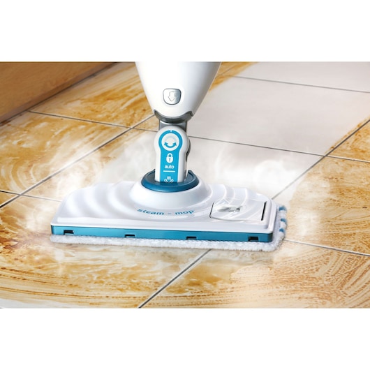 BLACK+DECKER FSMP20 balai vapeur nettoyant un sol carrelé sale, gros plan montrant la vapeur et l'action de nettoyage.