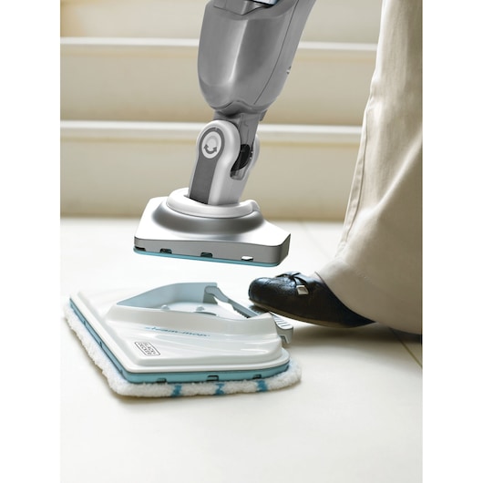 Accessoire de patin pour balai vapeur BLACKDECKER FSMP30 sur le sol, pied appuyant sur la pédale de libération, vue rapprochée.