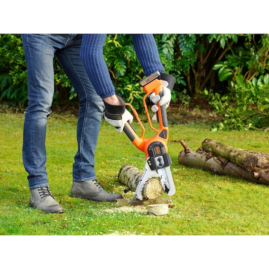 BLACKDECKER GKC1000L draadloze kettingzaag zaagt hout buiten, persoon met handschoenen.