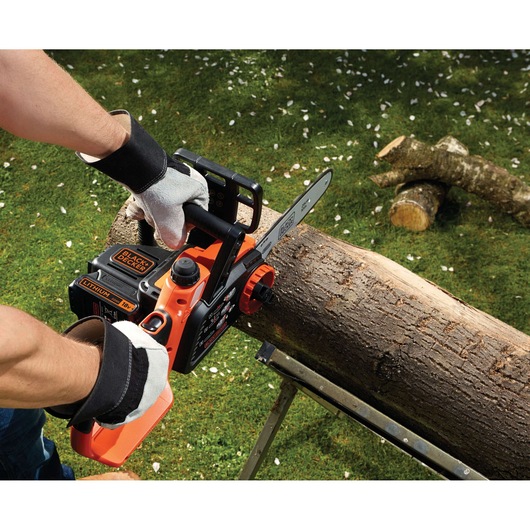 BLACKDECKER GKC1825LB lithium accu kettingzaag gebruikt voor het zagen van een stam buiten, close-up.