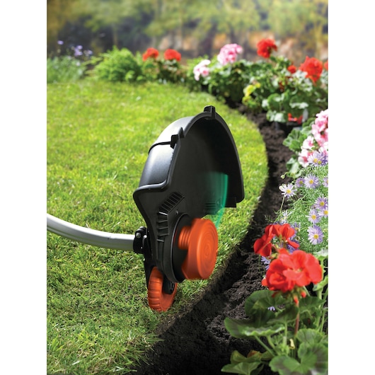 BLACKDECKER GL7033CAKIT grastrimmer randfotografie bij bloembed met oranje wiel en kap.