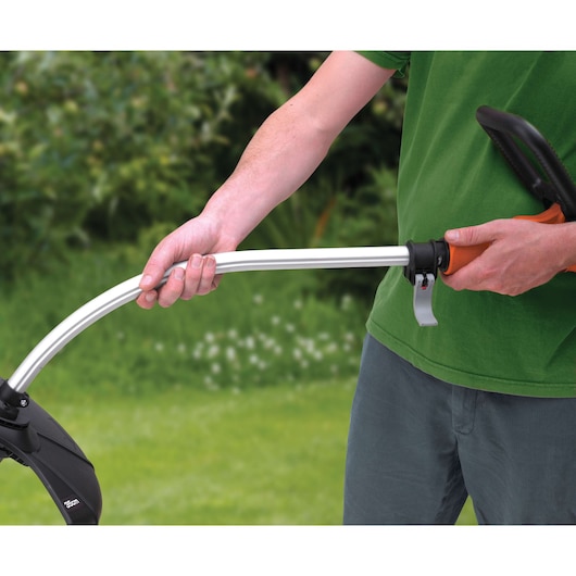 Foto van persoon die BLACKDECKER GL8033 grastrimmer handvat buiten vasthoudt.