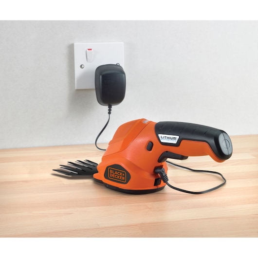 Foto van BLACK+DECKER GSL200 draadloze grasschaar met oplader, zijaanzicht op houten oppervlak.