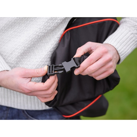BLACKDECKER GWBP1 fotografie van zwarte tasgesp met rode rand die door handen wordt vastgemaakt.