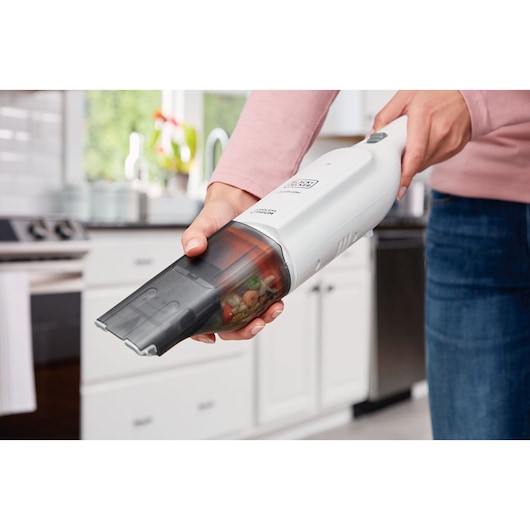 BLACKDECKER HLVC315B11 handstofzuiger in gebruik om kruimels in een keuken op te zuigen.