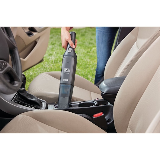 BLACK+DECKER HLVC320B11 handstofzuiger reinigt bekerhouder in beige auto-interieur.