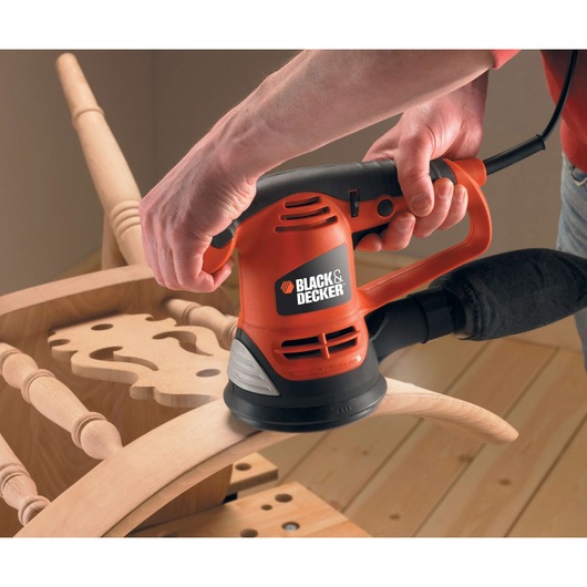 Foto van BLACK+DECKER KA191EK elektrische schuurmachine in gebruik op houten meubel.