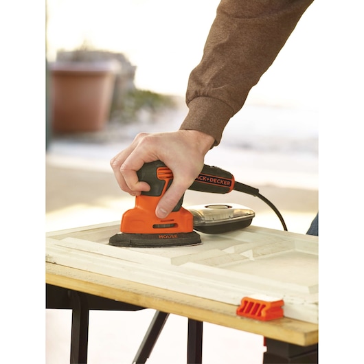Photo d'une ponceuse de détail BLACKDECKER KA2000 utilisée sur un panneau en bois.