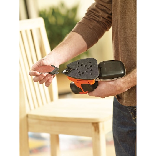Photo de la ponceuse de détail BLACKDECKER KA2000 tenue en main, accessoire en cours d'installation, intérieur.