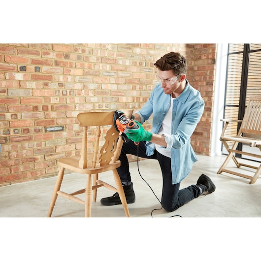 Fotografie van BLACKDECKER KA280LSA2 multisander gebruikt voor het schuren van een houten stoel binnen.