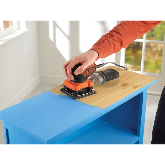 BLACKDECKER KA450 schuurmachine gebruikt op blauw geschilderd houten meubel, binnenruimte.