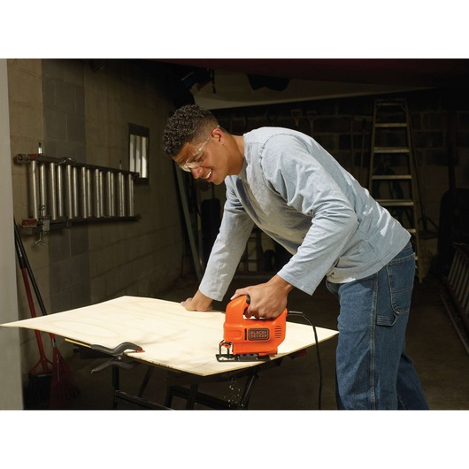 Foto van BLACKDECKER KS501 decoupeerzaag die een houten plank zaagt in werkplaats.
