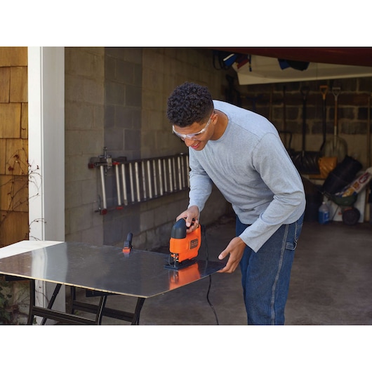 BLACKDECKER KS701E decoupeerzaag snijdt metalen plaat in een garagewerkplaats.