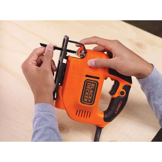 Foto van BLACKDECKER KS701E decoupeerzaag die wordt aangepast, oranje en zwart op houten oppervlak.