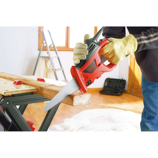 BLACKDECKER KS880EC scie électrique coupant du bois, angle latéral rapproché, utilisateur avec gants en atelier.