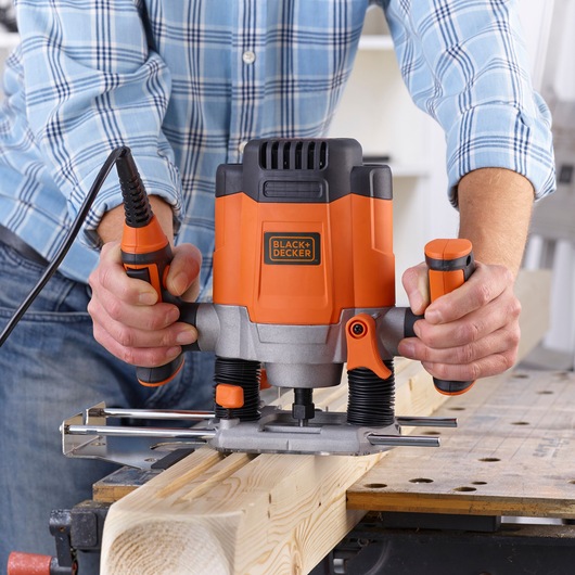 Outil défonceuse BLACK+DECKER KW1200EKA utilisé sur planche de bois, vue rapprochée avant.