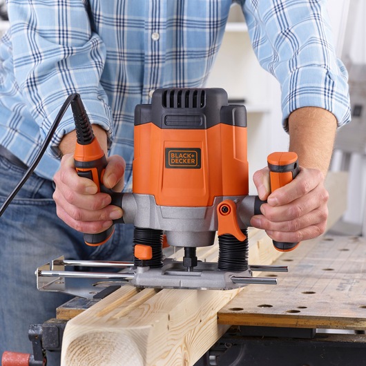 BLACKDECKER KW1200E défonceuse à bois utilisée sur une planche, design orange et noir.