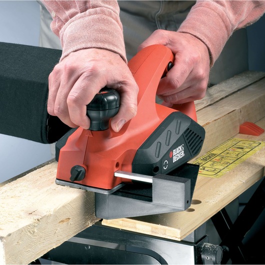 BLACKDECKER KW712KA rabot électrique utilisé sur une planche de bois, vue rapprochée.