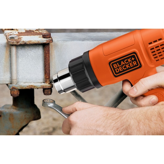 BLACK+DECKER KX1650 heteluchtpistool gebruikt op een verroeste metalen bout met sleutel, close-up.