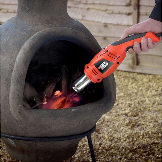 BLACKDECKER KX1692 heteluchtpistool steekt hout aan in buitenhaard, close-up fotografie.