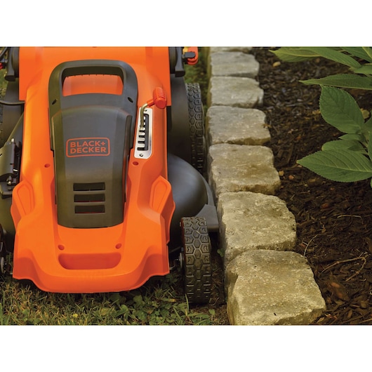 BLACK+DECKER LM2000 grasmaaier close-up, maait precies langs stenen rand en tuinbed.